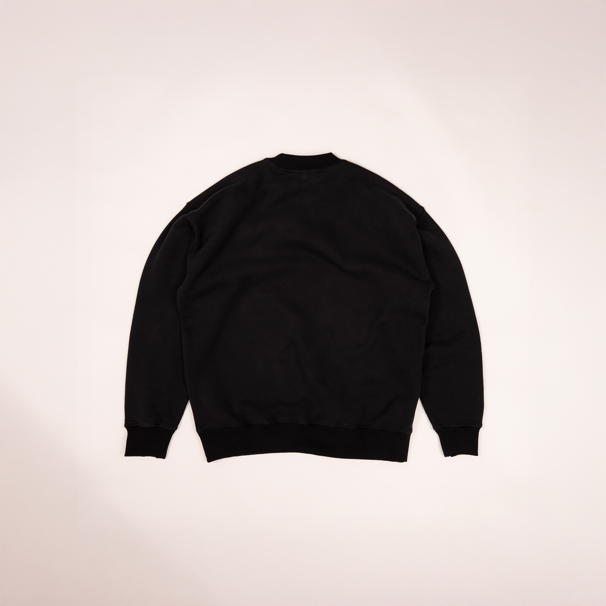 Back view of The Crew Sweatshirt in black by Studio Nidra, laying flat on light background.
